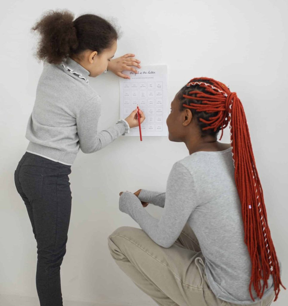 mom and daughter write on wall calendar