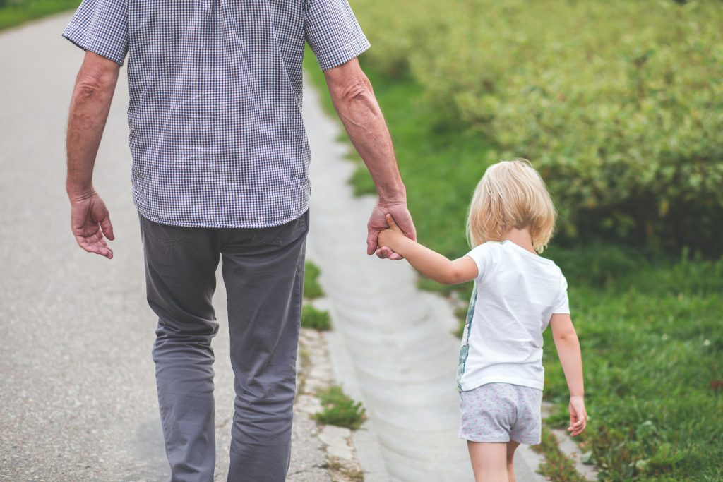 little blond girl holds hands with dad