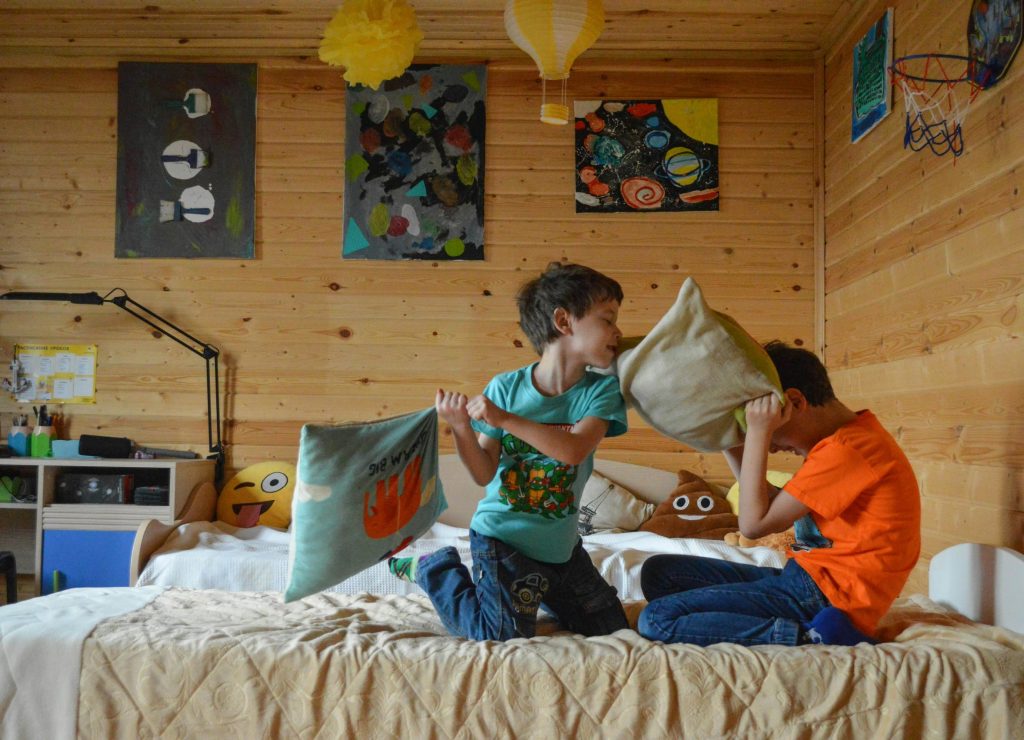 two boys pillow fight on bed